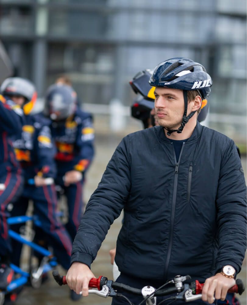 Max Verstappen in cinema surrounded by Red Bull Racing pit crew in helmets